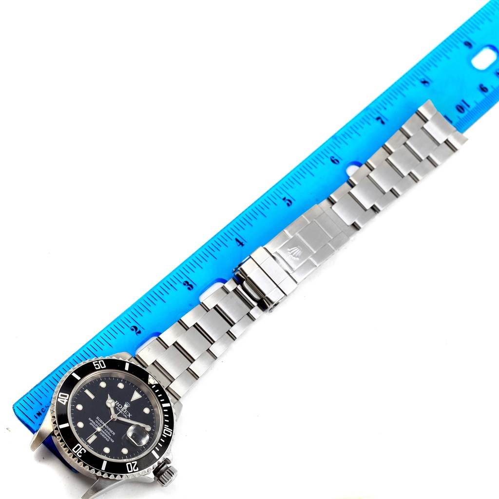 The image shows a Rolex Submariner 16610 Men's Stainless Steel Black Dial 16610 Men's Stainless Steel Black Dial watch laid flat, displaying the face, bracelet, and clasp next to a ruler for size reference.