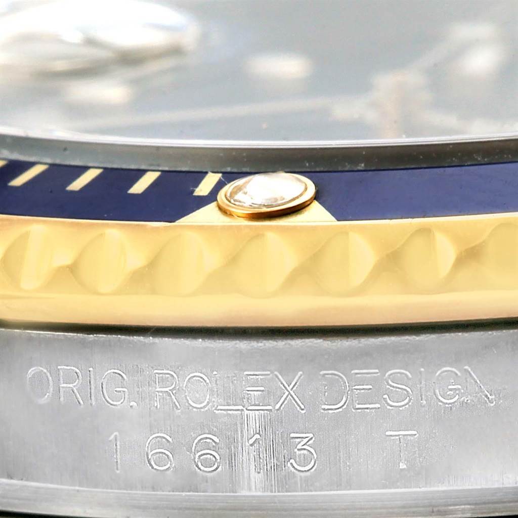 The image shows a close-up of the bezel and case edge of a Rolex Submariner 16613 Men's Steel and Gold (two tone) Blue Dial 16613 Men's Steel and Gold (two tone) Blue Dial with engraving on the side.
