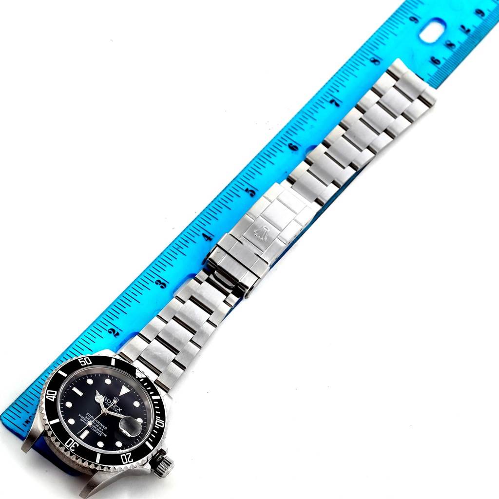 The image shows a top view of a Rolex Submariner 16610 Men's Stainless Steel Black Dial 16610 Men's Stainless Steel Black Dial watch, focusing on the face, bezel, and bracelet with a ruler for scale.