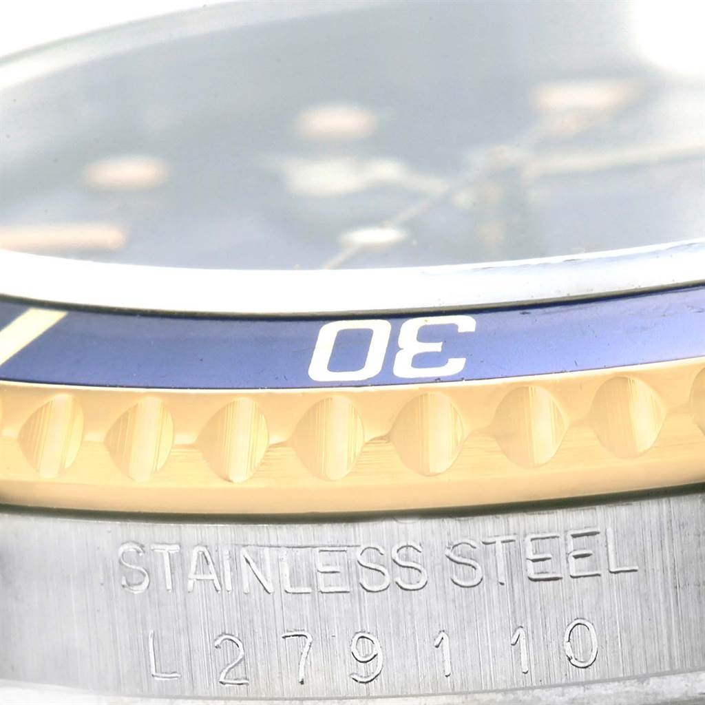 This close-up of the Rolex Submariner 16613 Men's Steel and Gold (two tone) Blue Dial 16613 Men's Steel and Gold (two tone) Blue Dial watch shows part of the bezel with the number 30 and the case engraved with "STAINLESS STEEL" and a serial number.