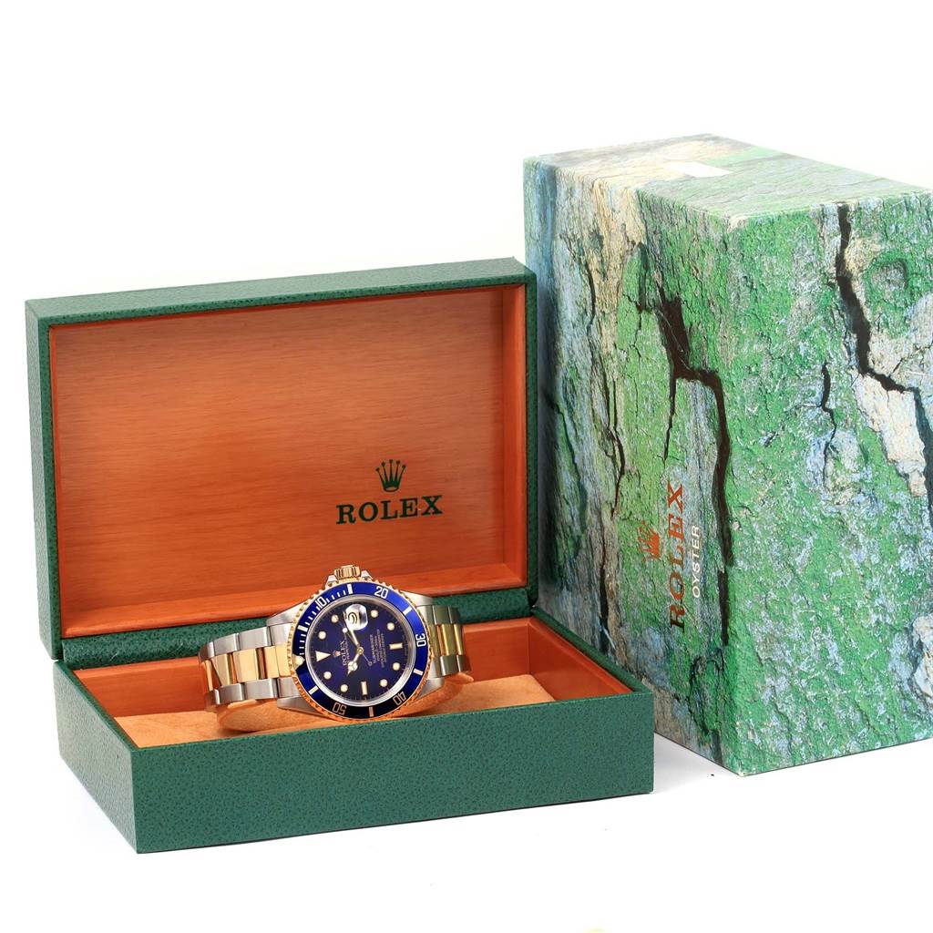 The Rolex Submariner 16613 Men's Steel and Gold (two tone) Blue Dial 16613 Men's Steel and Gold (two tone) Blue Dial watch is shown from the front in its open box, accompanied by the green Rolex packaging.