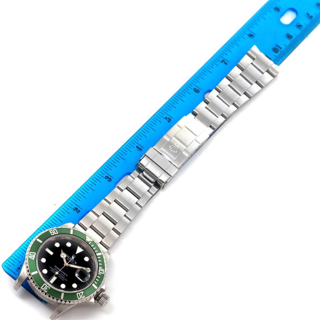 The Rolex Submariner 16610LV Men's Stainless Steel Black Dial 16610LV Men's Stainless Steel Black Dial watch is shown lying flat with a blue ruler next to it, displaying the watch face and bracelet.