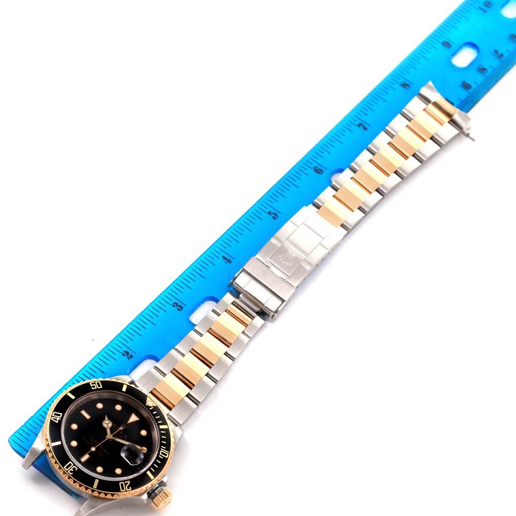This image shows a Rolex Submariner 16613 Men
s Steel and Gold (two tone) Black Dial 16613 Men
s Steel and Gold (two tone) Black Dial watch laid flat with a ruler measuring its bracelet length.