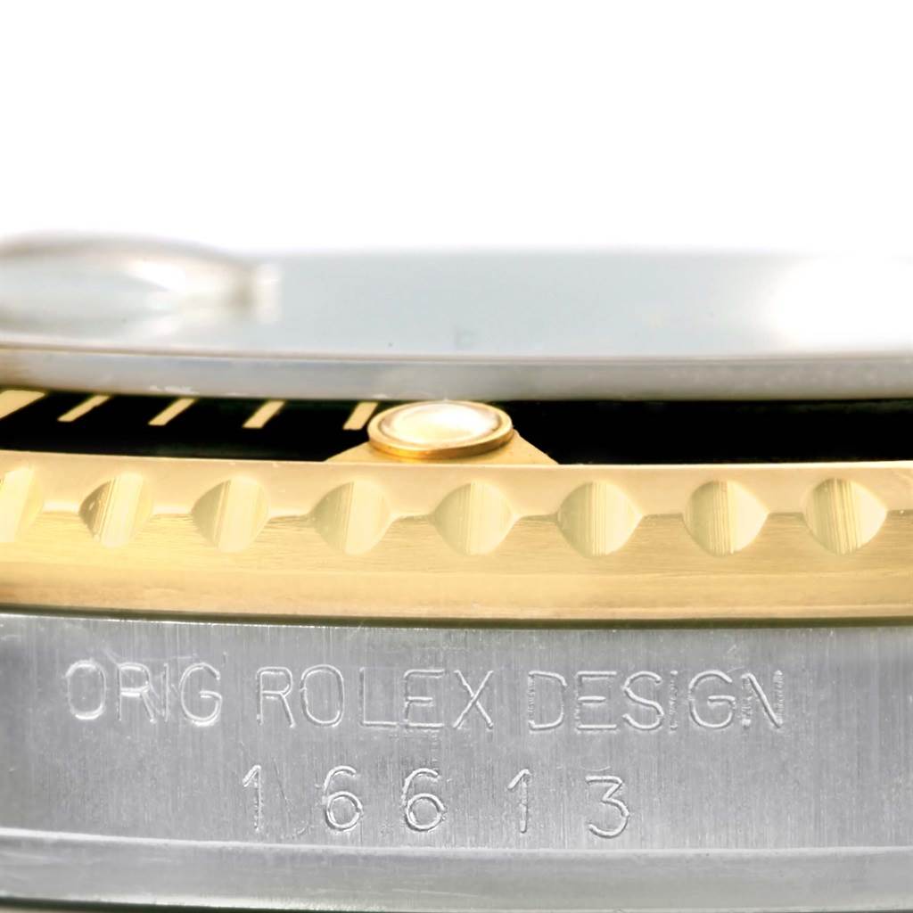 Close-up of a Rolex Submariner 16613 Men
s Steel and Gold (two tone) Black Dial 16613 Men
s Steel and Gold (two tone) Black Dial model showing the bezel, a part of the dial, and engraved design numbers.