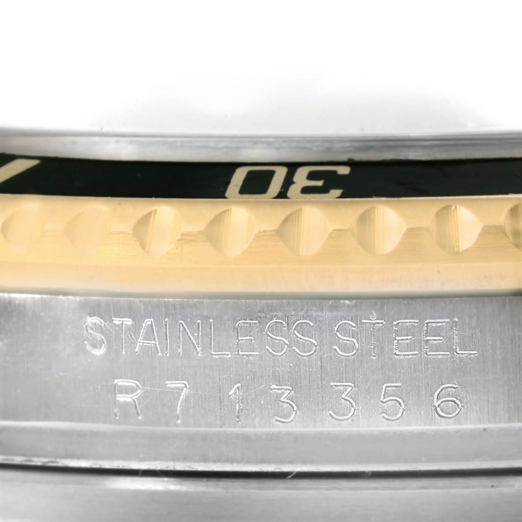 The image shows a close-up angle of the Rolex Submariner 16613 Men
s Steel and Gold (two tone) Black Dial 16613 Men
s Steel and Gold (two tone) Black Dial watch
s steel case, engravings, and part of the bezel edge.