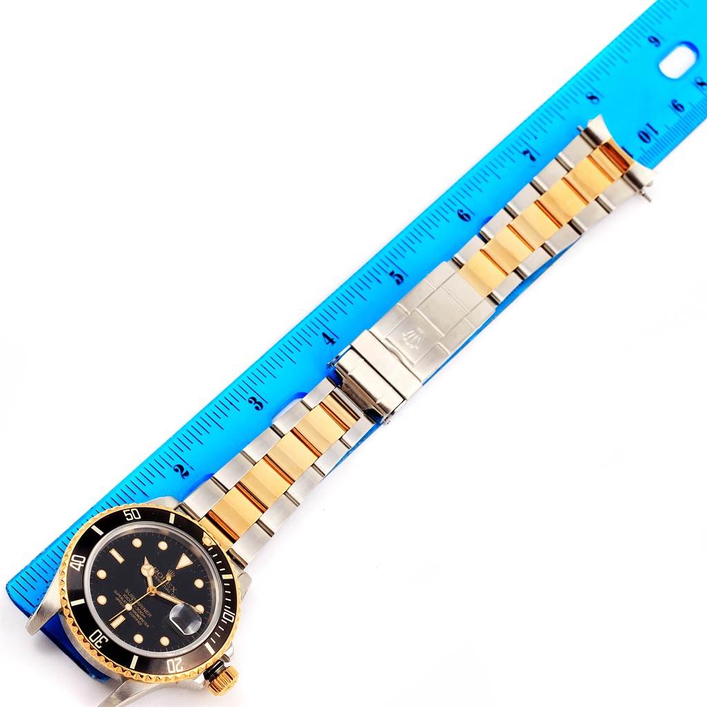 The image shows the full length of a Rolex Submariner 16803 Men
s Steel and Gold (two tone) Black Dial 16803 Men
s Steel and Gold (two tone) Black Dial watch, including the case, bezel, dial, and two-tone bracelet, alongside a ruler for scale.