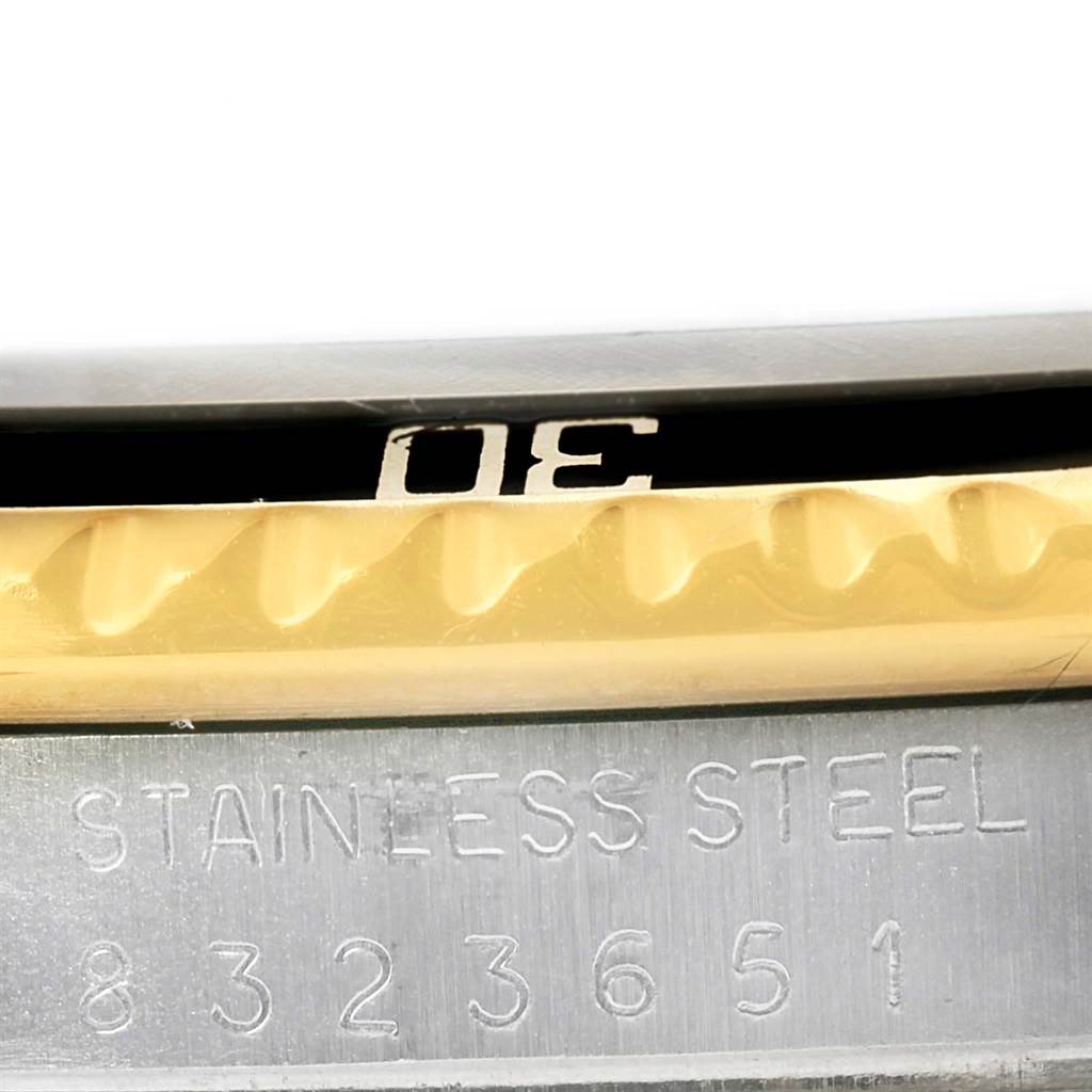 This close-up image shows the side engraving and part of the bezel of a Rolex Submariner 16803 Men
s Steel and Gold (two tone) Black Dial 16803 Men
s Steel and Gold (two tone) Black Dial watch.