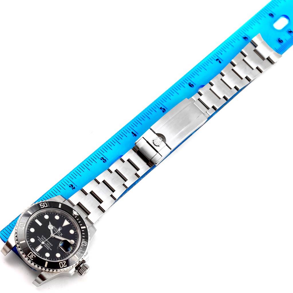 The image shows a side view of a Rolex Submariner 116610 Men's Stainless Steel Black Dial 116610 Men's Stainless Steel Black Dial watch with its stainless steel bracelet next to a blue ruler for measurement.