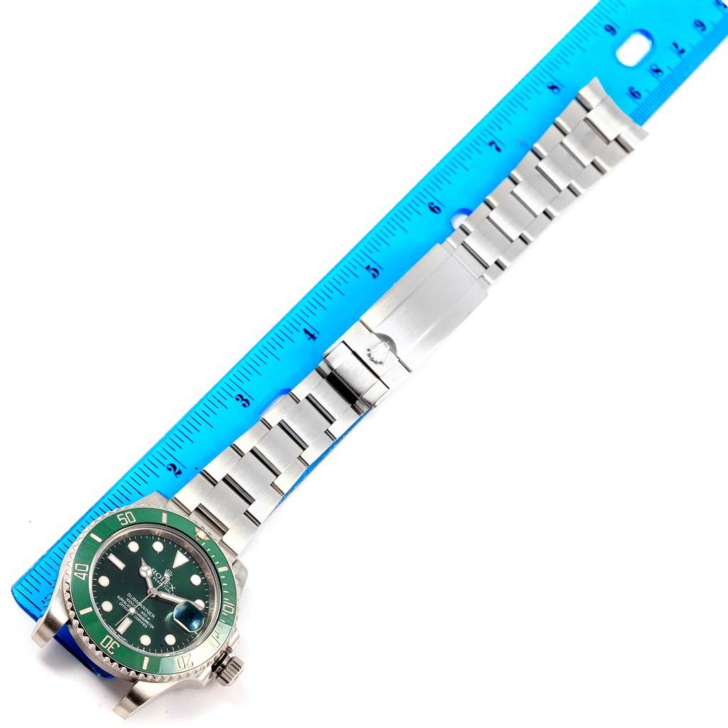 The Rolex Submariner 116610LV Men's Stainless Steel Green Dial 116610LV Men's Stainless Steel Green Dial watch is shown laid flat, displaying the green dial, bezel, and metal bracelet, with a ruler for scale.