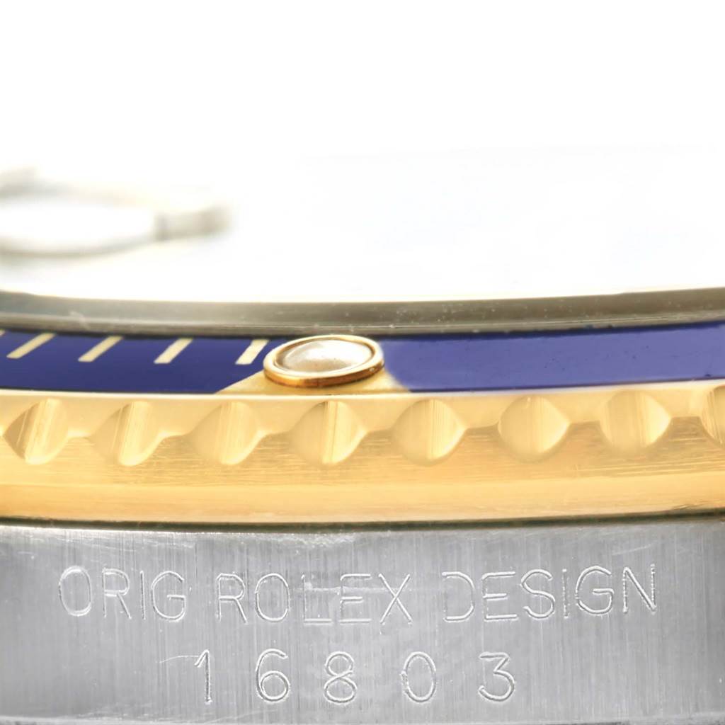 The image shows a close-up angle of the bezel, and case edge, engraving of the model "16803" of the Rolex Submariner 16803 Men's Steel and Gold (two tone) Blue Dial 16803 Men's Steel and Gold (two tone) Blue Dial watch.