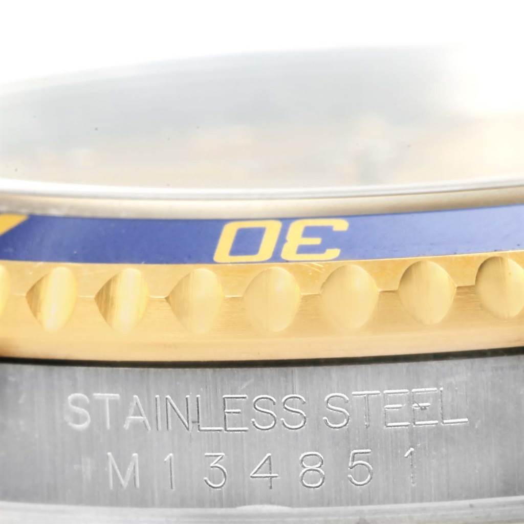 This image shows a close-up of a Rolex Submariner 16613 Men's Steel and Gold (two tone) Champagne Dial 16613 Men's Steel and Gold (two tone) Champagne Dial watch focusing on the bezel edge and the engraved serial number on the stainless steel case.