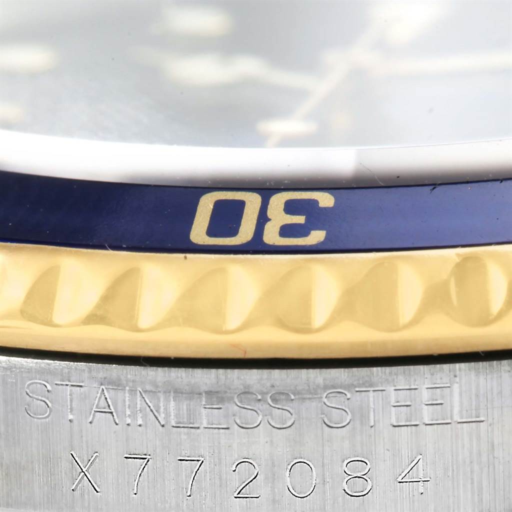 The image shows a close-up of a Rolex Submariner 16613 Men
s Steel and Gold (two tone) Blue Dial 16613 Men
s Steel and Gold (two tone) Blue Dial watch, highlighting the bezel, part of the dial, and the engraved serial number.