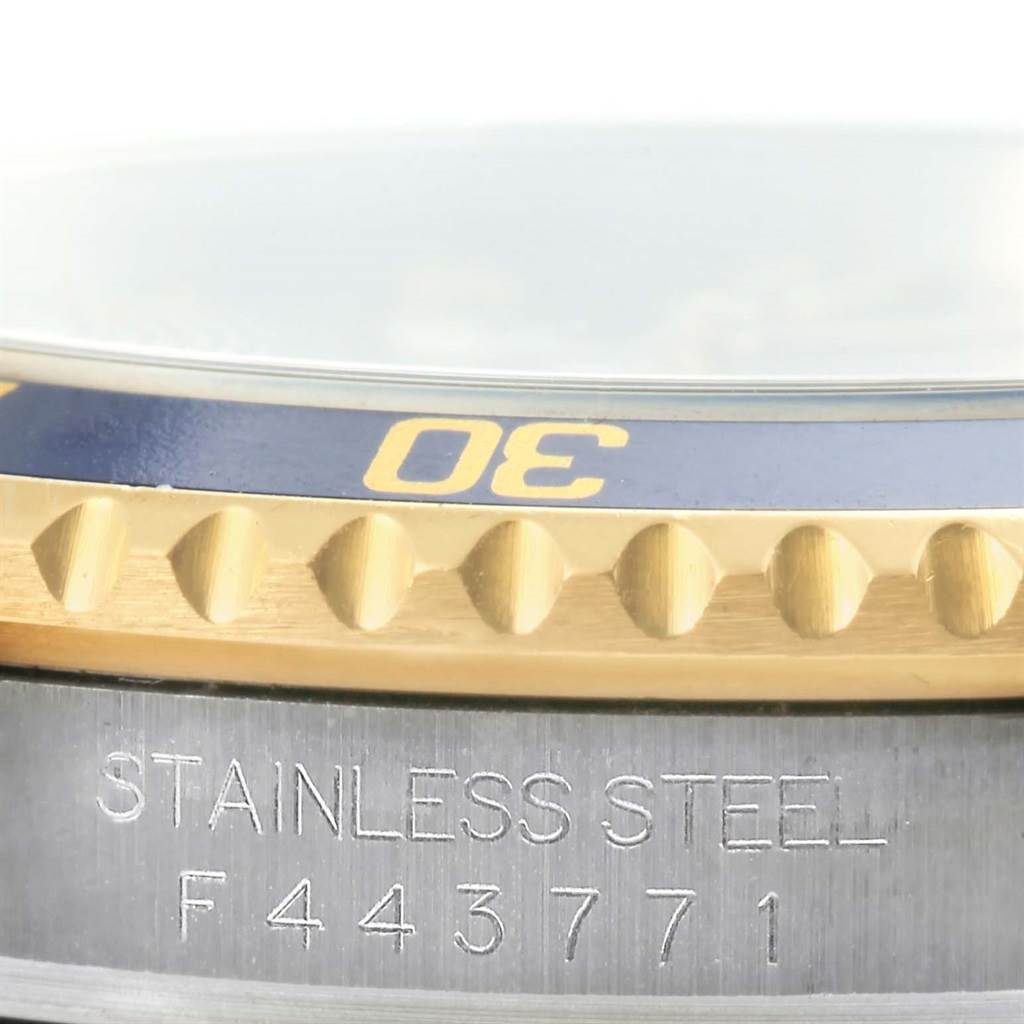 The image shows the side view of a Rolex Submariner 16613 Men
s Steel and Gold (two tone) Grey Dial 16613 Men
s Steel and Gold (two tone) Grey Dial watch featuring its bezel and part of its stainless steel case with the serial number visible.