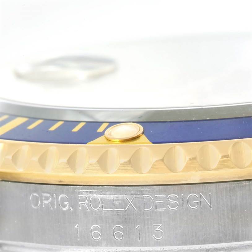 This close-up image of the Rolex Submariner 16613 Men's Steel and Gold (two tone) Champagne Dial 16613 Men's Steel and Gold (two tone) Champagne Dial shows the engraved bezel, part of the crown guard, and reference number 16613.