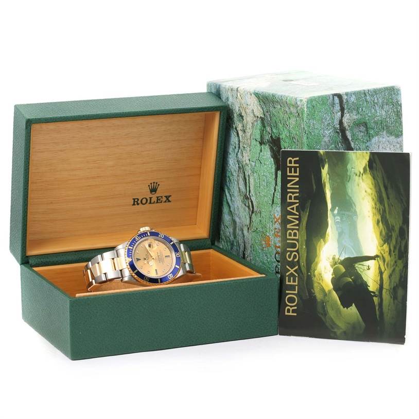 The image shows a Rolex Submariner 16613 Men's Steel and Gold (two tone) Champagne Dial 16613 Men's Steel and Gold (two tone) Champagne Dial watch inside its open green box, with its booklet displayed beside it.