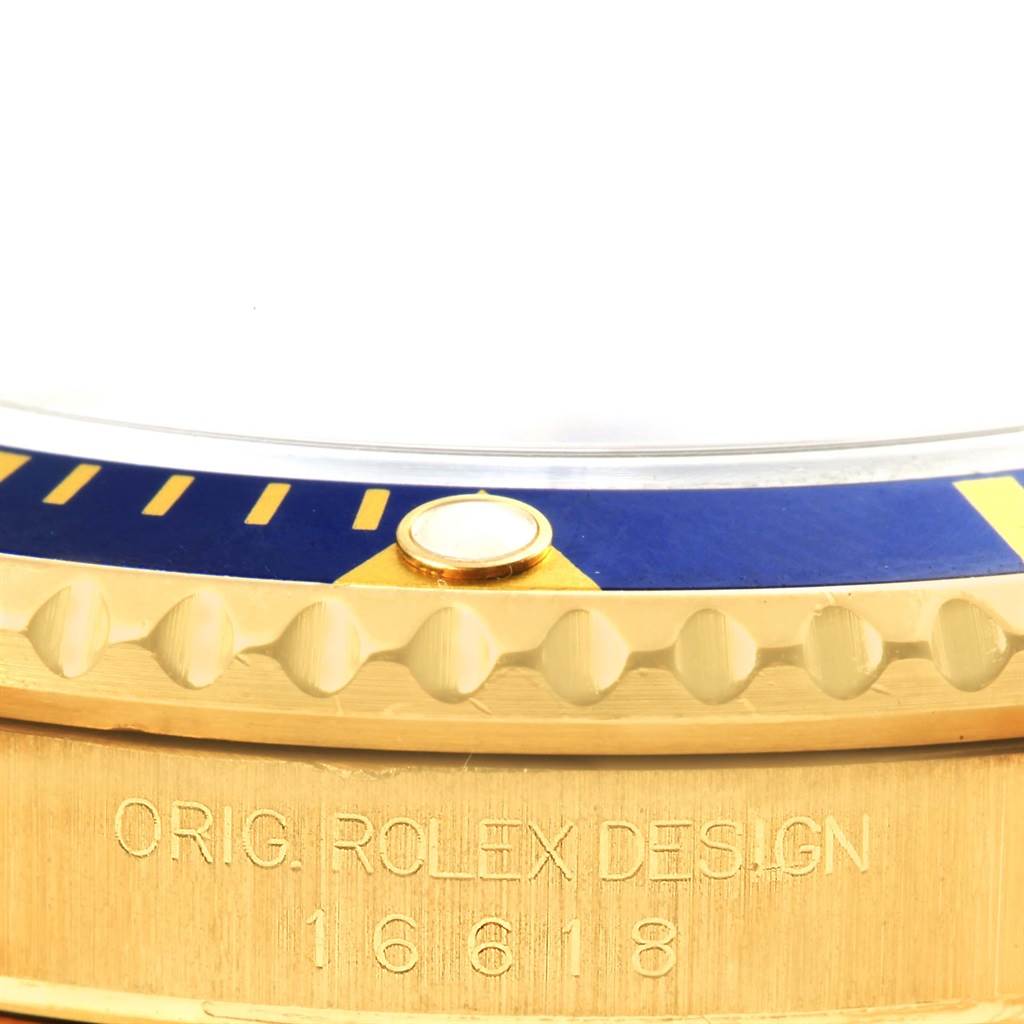 This image shows a close-up of the bezel and part of the case of a Rolex Submariner 16618 Men's Yellow Gold Blue Dial 16618 Men's Yellow Gold Blue Dial watch.