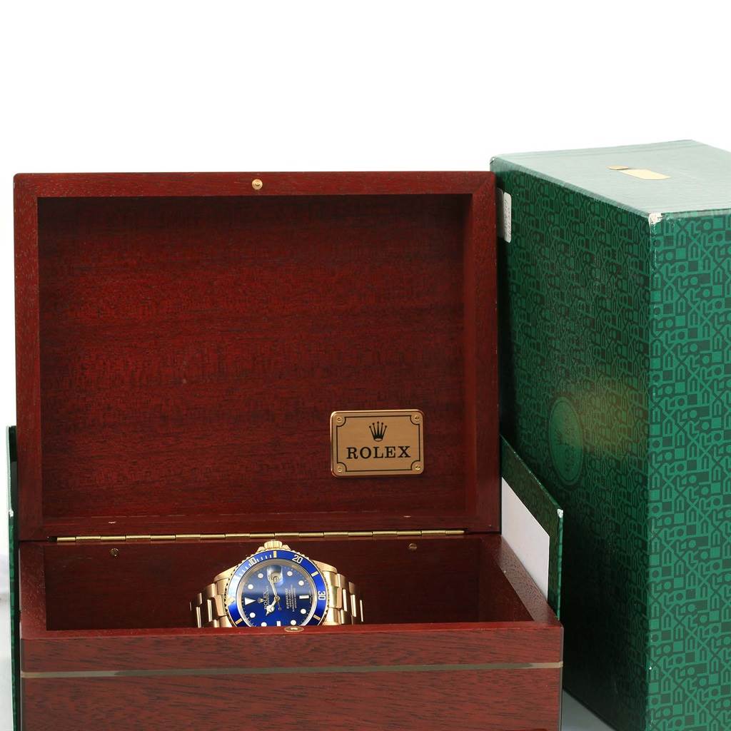 The image shows a Rolex Submariner 16618 Men's Yellow Gold Blue Dial 16618 Men's Yellow Gold Blue Dial watch inside an open wooden Rolex box, with a green outer box to the right.