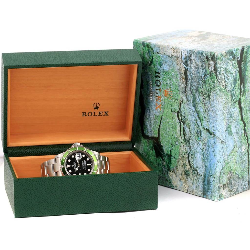 A Rolex Submariner 16610LV Men's Stainless Steel Black Dial 16610LV Men's Stainless Steel Black Dial watch is shown inside an open green and wood-colored box, with an outer green-textured box beside it.