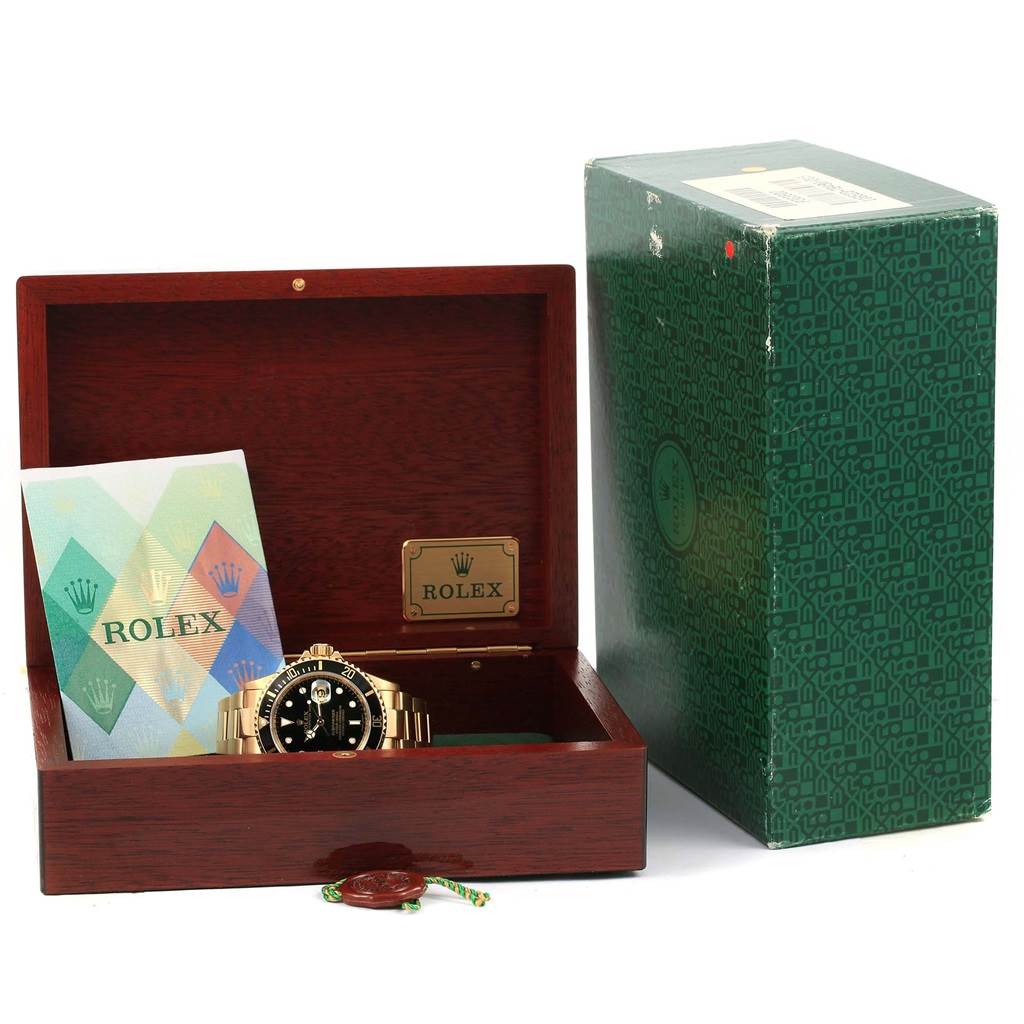 The image shows a Rolex Submariner 16618 Men's Yellow Gold Black Dial 16618 Men's Yellow Gold Black Dial watch in a wooden box with its paperwork and outer green packaging.