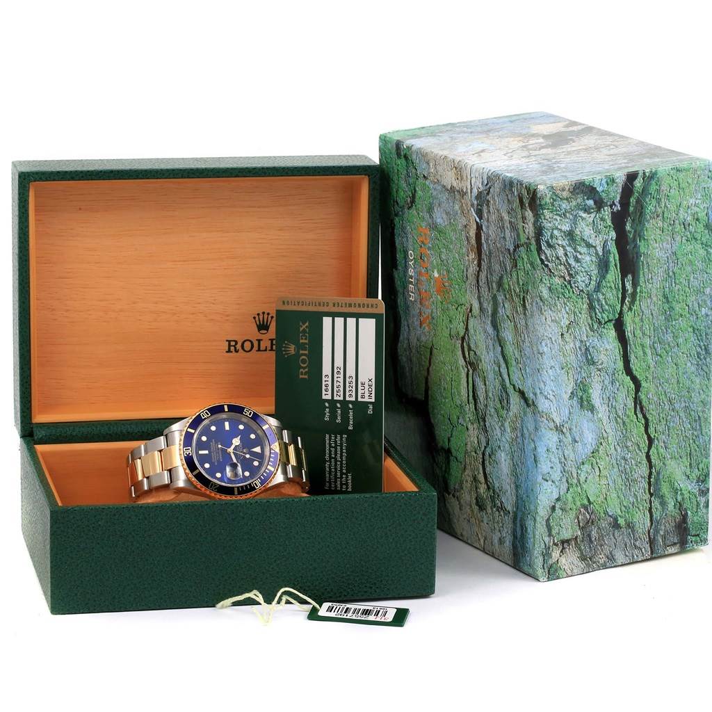 The Rolex Submariner 16613 Men's Steel and Gold (two tone) Blue Dial 16613 Men's Steel and Gold (two tone) Blue Dial watch is displayed in an open box with an accompanying authenticity card and tags, alongside its external box.