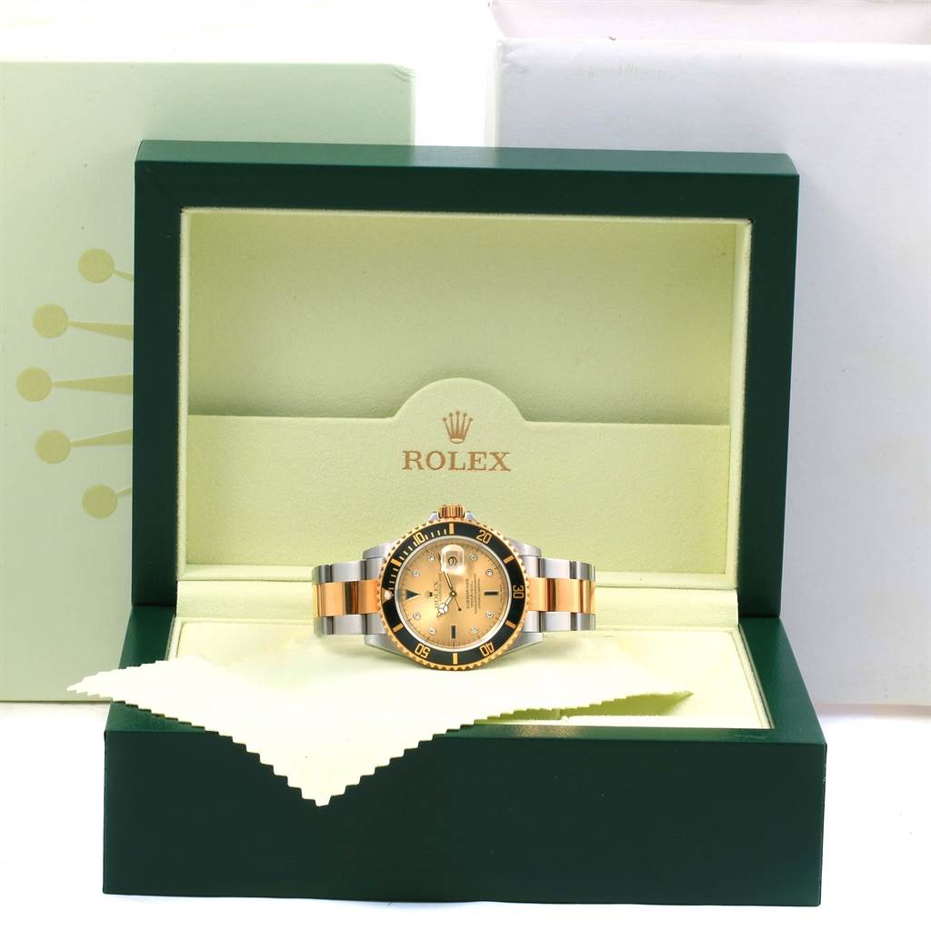 The Rolex Submariner 16613 Men's Steel and Gold (two tone) Champagne Dial 16613 Men's Steel and Gold (two tone) Champagne Dial watch is displayed front-on in its open green box with visible brand logo and packaging.