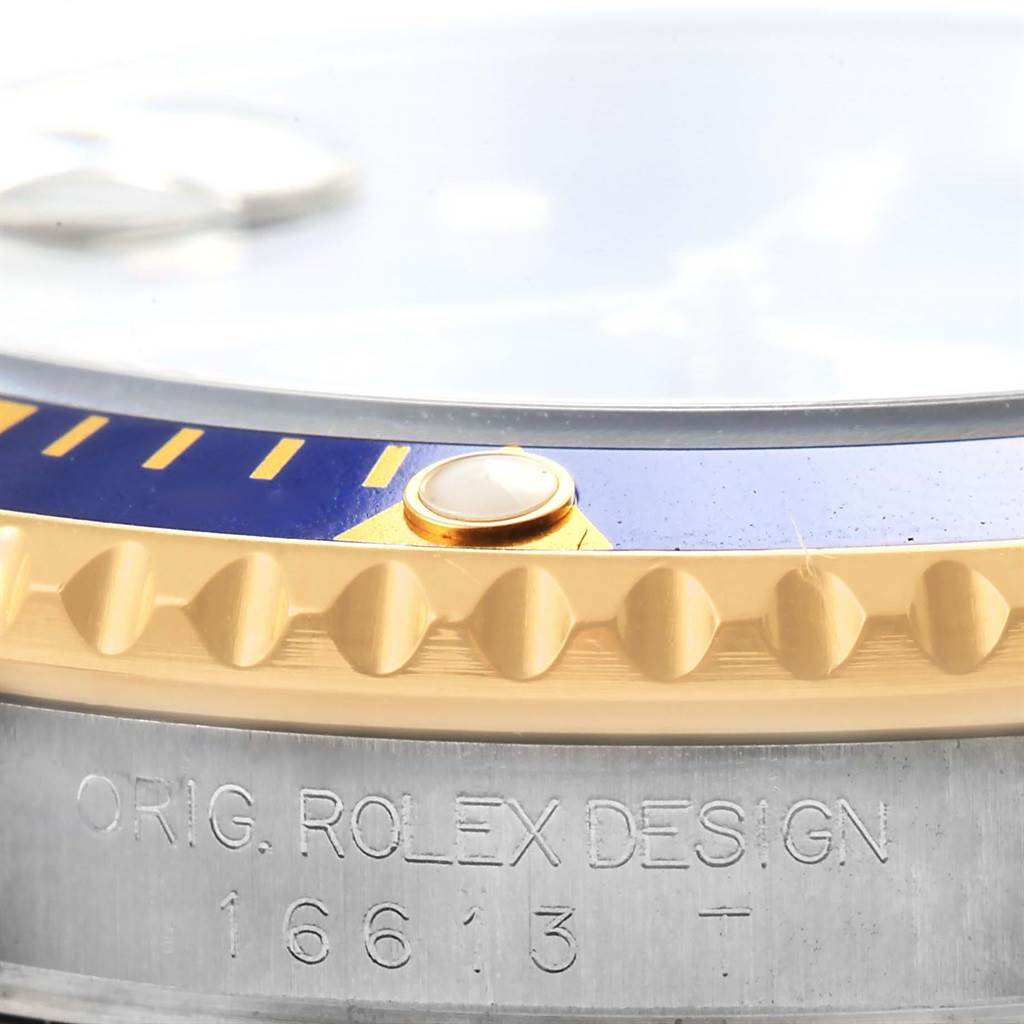 The image shows a close-up of the side and bezel of a Rolex Submariner 16613 Men's Steel and Gold (two tone) Blue Dial 16613 Men's Steel and Gold (two tone) Blue Dial, highlighting the engraved text and crown.