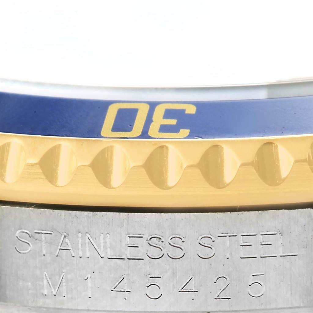 This image shows a close-up of the bezel and part of the case back, engraved with "STAINLESS STEEL M145425," of a Rolex Submariner 16613 Men's Steel and Gold (two tone) Blue Dial 16613 Men's Steel and Gold (two tone) Blue Dial watch.
