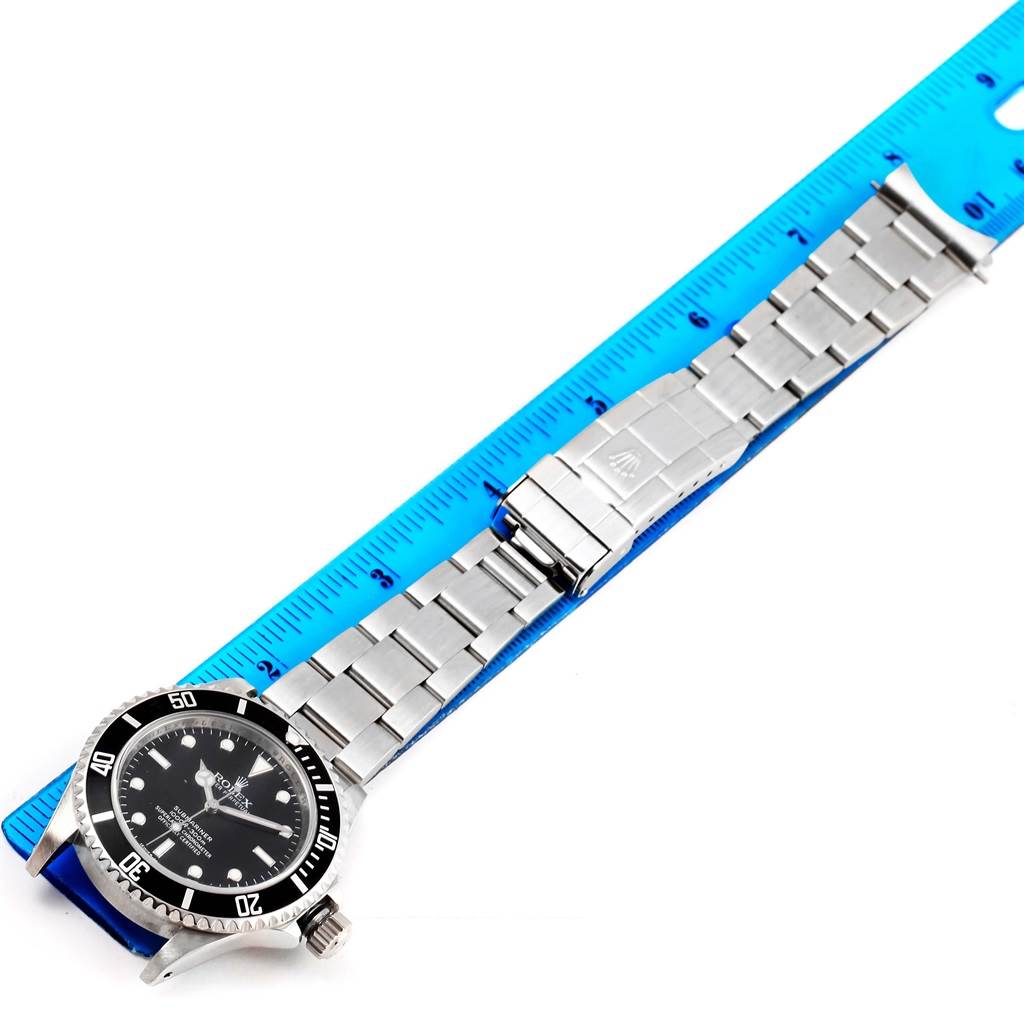 This image shows the Rolex Submariner 14060 Men's Stainless Steel Black Dial 14060 Men's Stainless Steel Black Dial watch laid flat with the bracelet extended, alongside a ruler for scale.