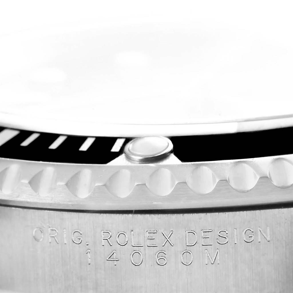 This close-up image of the Rolex Submariner 14060 Men's Stainless Steel Black Dial 14060 Men's Stainless Steel Black Dial watch shows the bezel, part of the sapphire crystal, and the model engravings.