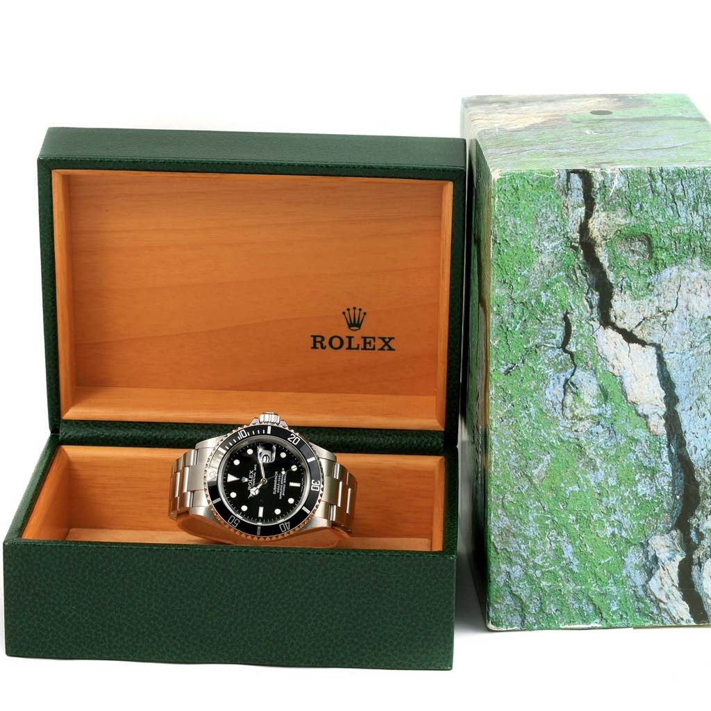 The image shows a Rolex Submariner 16610 Men's Stainless Steel Black Dial 16610 Men's Stainless Steel Black Dial watch placed inside its open green and wooden box, with the box's lid propped upwards.
