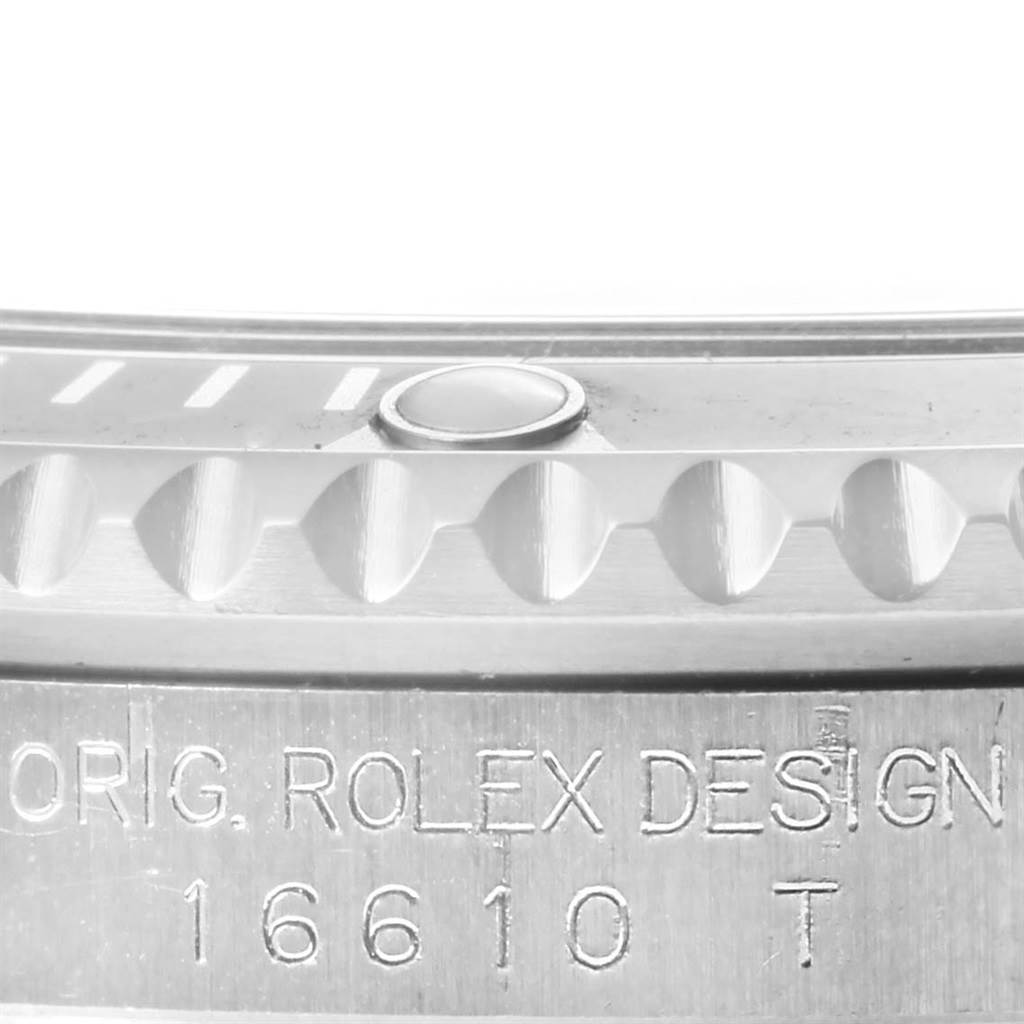 This close-up image of the Rolex Submariner 16610 Men's Stainless Steel Black Dial 16610 Men's Stainless Steel Black Dial shows the model number 16610 T and part of the bezel with minute markers.
