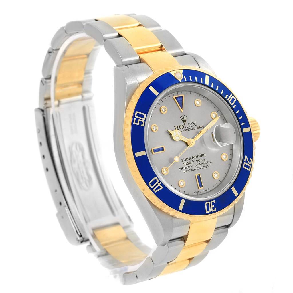 The Rolex Submariner 16613 Men
s Steel and Gold (two tone) Grey Dial 16613 Men
s Steel and Gold (two tone) Grey Dial watch is shown from a three-quarter angle, highlighting the bezel, dial, bracelet, and clasp.