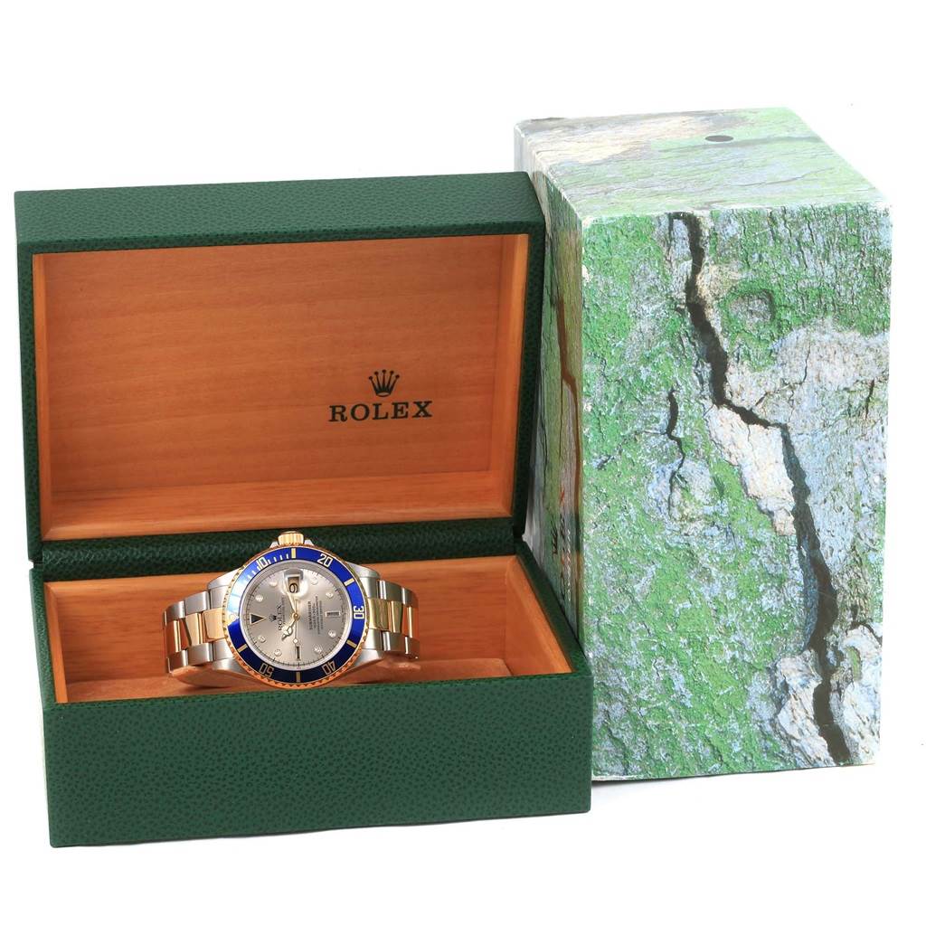 The image shows a Rolex Submariner 16613 Men
s Steel and Gold (two tone) Grey Dial 16613 Men
s Steel and Gold (two tone) Grey Dial watch displayed in an open green and wooden box, with an outer green decorative box.