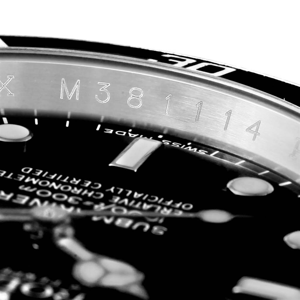 This close-up image of a Rolex Submariner 16610 Men's Stainless Steel Black Dial 16610 Men's Stainless Steel Black Dial shows part of the case, bezel, and dial with engraved numbers and text.