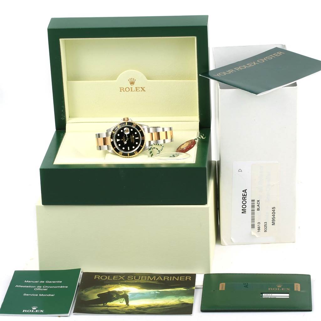The image shows a Rolex Submariner 16613 Men
s Steel and Gold (two tone) Black Dial 16613 Men
s Steel and Gold (two tone) Black Dial watch at a frontal angle, along with its box, manuals, and warranty card.