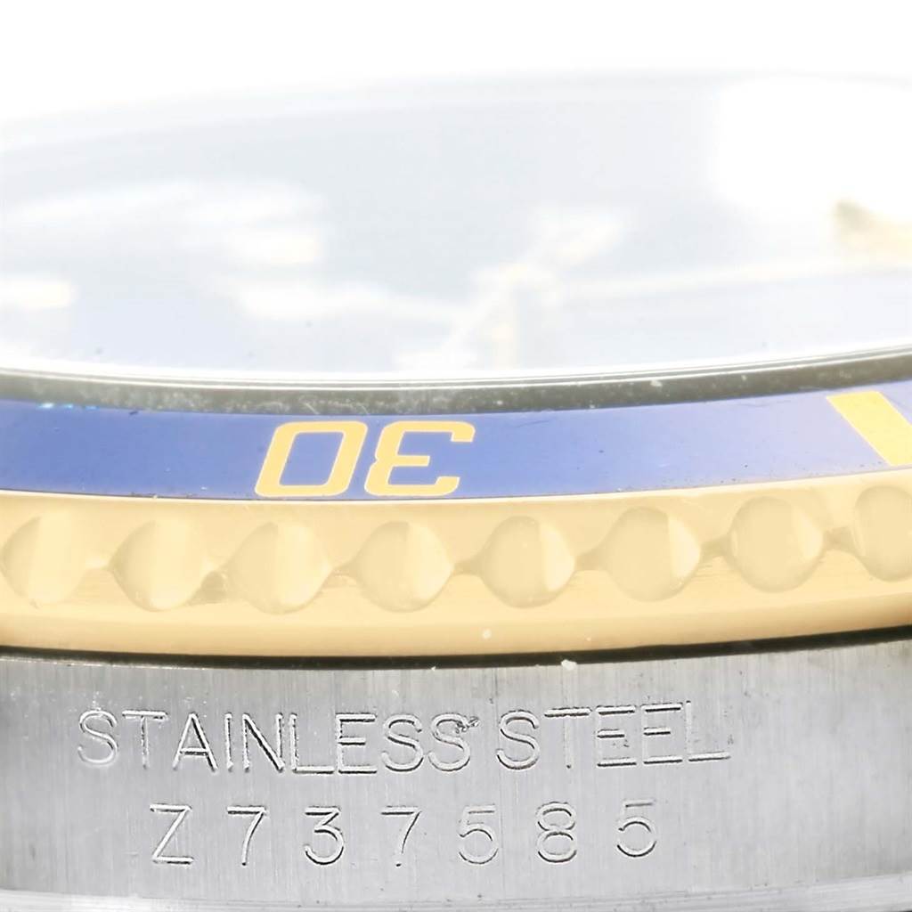 The image shows a close-up side view of a Submariner model by Rolex, highlighting the bezel and part of the stainless steel case with an engraving.