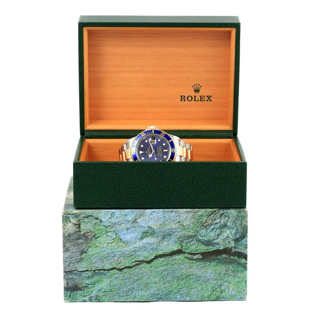 The image shows a Rolex Submariner 16613 Men's Steel and Gold (two tone) Blue Dial 16613 Men's Steel and Gold (two tone) Blue Dial watch in an open green and wooden Rolex box, viewed from the front.