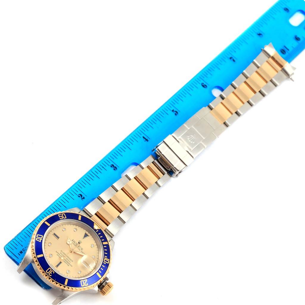 This image shows a top view of a Rolex Submariner 16613 Men's Steel and Gold (two tone) Champagne Dial 16613 Men's Steel and Gold (two tone) Champagne Dial watch placed next to a ruler, highlighting its face, bezel, and bracelet.