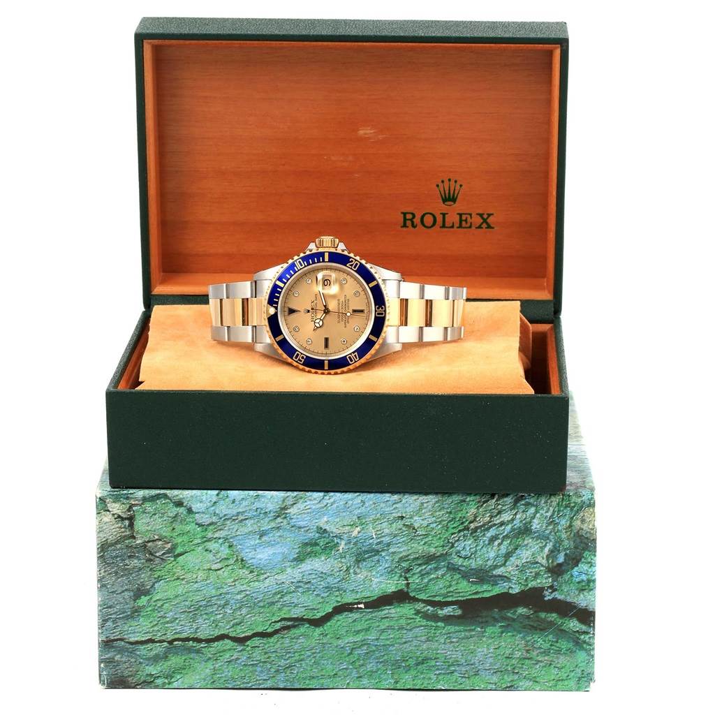 The Rolex Submariner 16613 Men's Steel and Gold (two tone) Champagne Dial 16613 Men's Steel and Gold (two tone) Champagne Dial watch is displayed front-on, showing its face, bezel, bracelet, and brand packaging.