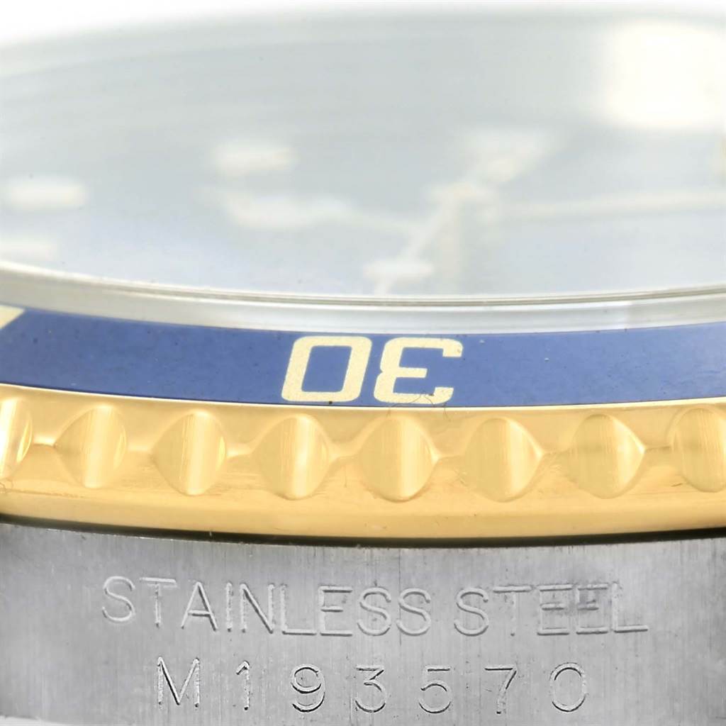 The image shows a close-up of a Rolex Submariner 16613 Men's Steel and Gold (two tone) Blue Dial 16613 Men's Steel and Gold (two tone) Blue Dial's bezel and part of the engraved case back.