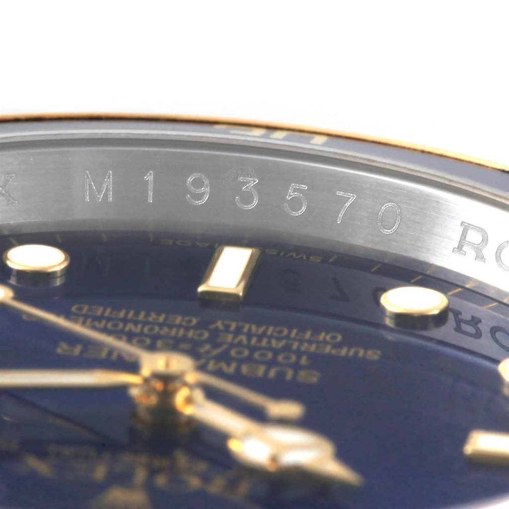 This close-up shows the serial number and part of the dial and hands of a Rolex Submariner 16613 Men's Steel and Gold (two tone) Blue Dial 16613 Men's Steel and Gold (two tone) Blue Dial watch.