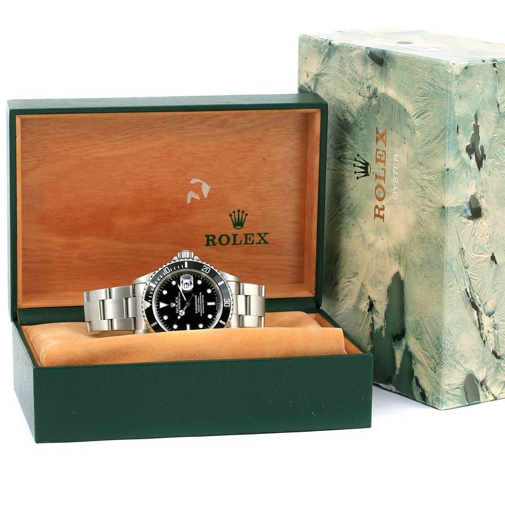 The Rolex Submariner 16610 Men's Stainless Steel Black Dial 16610 Men's Stainless Steel Black Dial watch is displayed at a straight angle in an open green and wooden box with a lid bearing the Rolex logo.