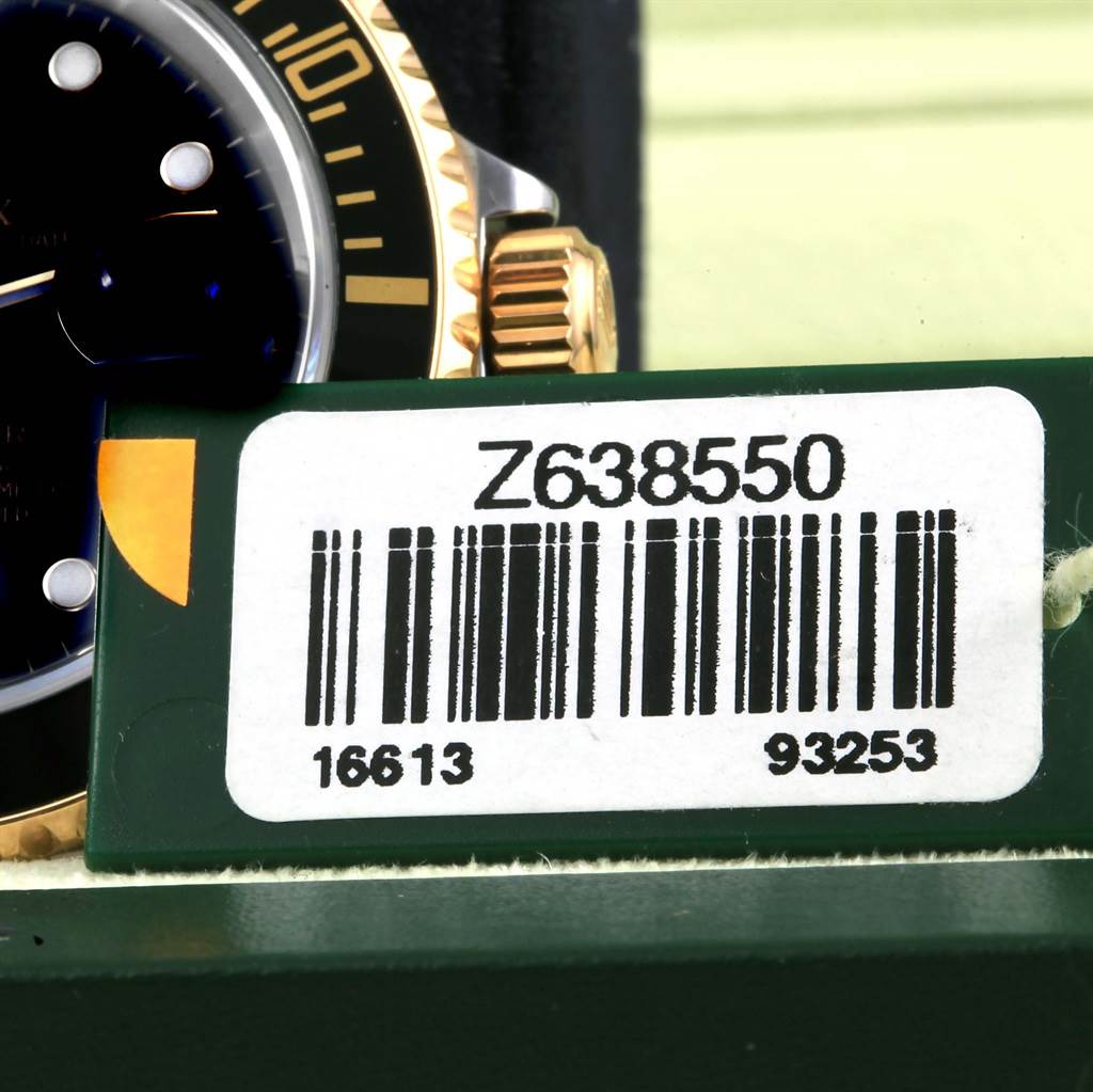 The close-up image shows the right side of a Rolex Submariner 16613 Men's Steel and Gold (two tone) Black Dial 16613 Men's Steel and Gold (two tone) Black Dial watch including part of the bezel, crown, and tag with barcode.