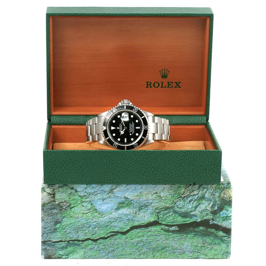 The Rolex Submariner 16610 Men's Stainless Steel Black Dial 16610 Men's Stainless Steel Black Dial watch is shown from the front, displayed in an open green and wooden Rolex box.