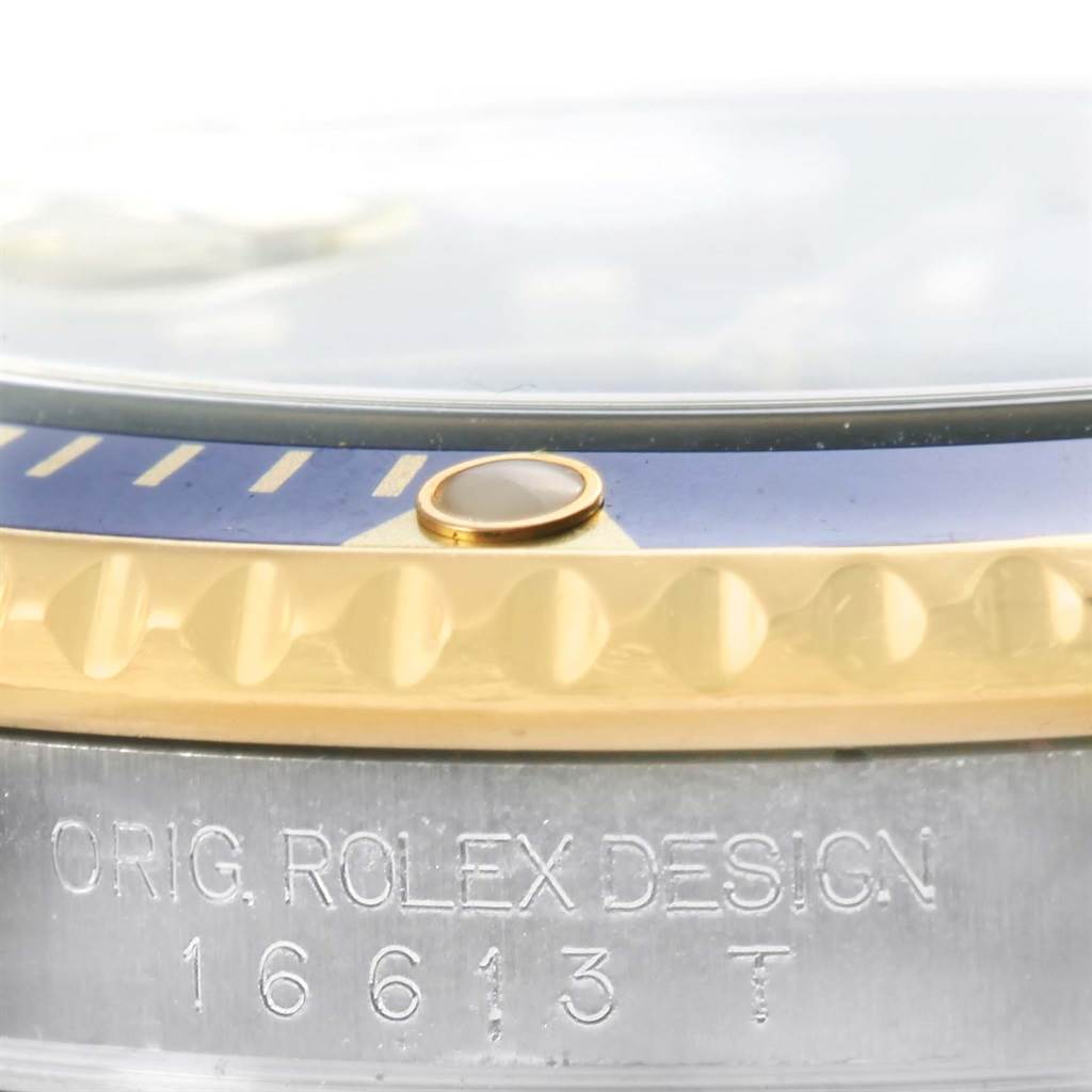 Close-up of the bezel, case, and engraving on a Rolex Submariner 16613 Men's Steel and Gold (two tone) Blue Dial 16613 Men's Steel and Gold (two tone) Blue Dial model, showing part of the serial number.