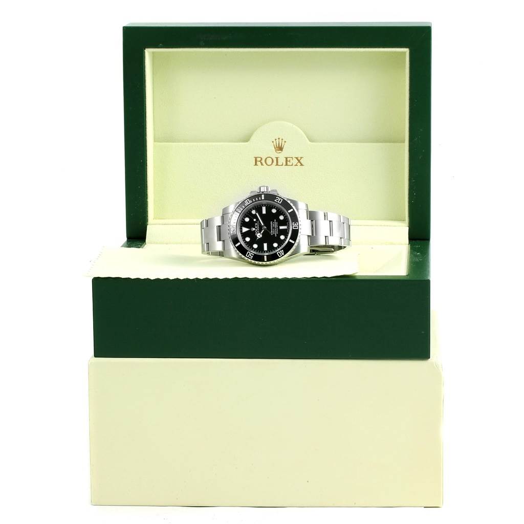 The Rolex Submariner 114060 Men's Stainless Steel Black Dial 114060 Men's Stainless Steel Black Dial watch is displayed head-on, inside its open green and cream-colored box.