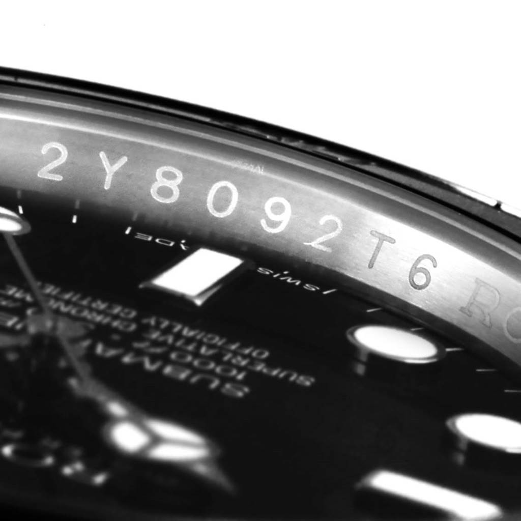 The image shows the serial number and part of the dial of a Rolex Submariner 114060 Men's Stainless Steel Black Dial 114060 Men's Stainless Steel Black Dial watch at an angle.
