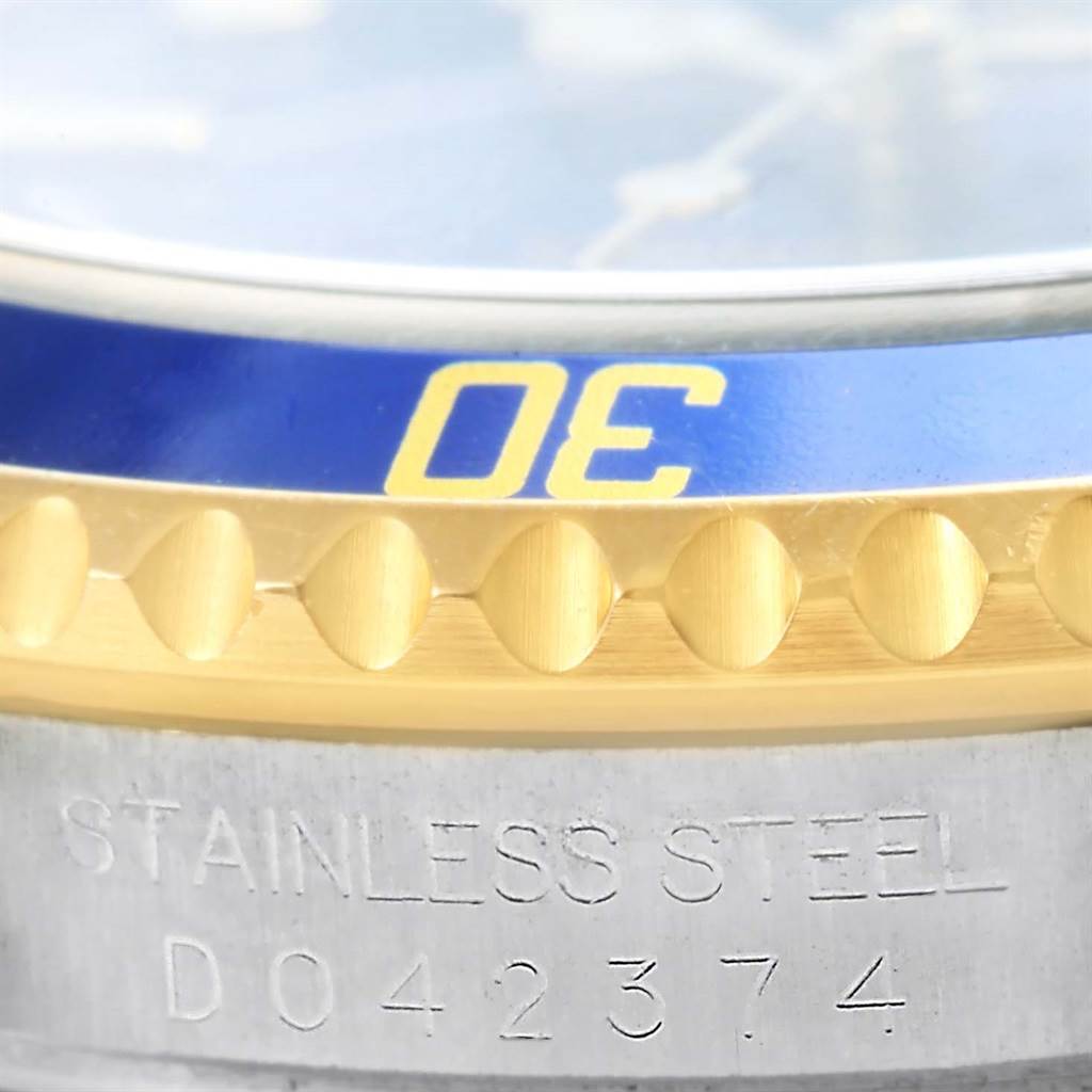 This close-up image of a Rolex Submariner 16613 Men
s Steel and Gold (two tone) Blue Dial 16613 Men
s Steel and Gold (two tone) Blue Dial watch shows the bezel, dial edge, and part of the case, including engraved text.