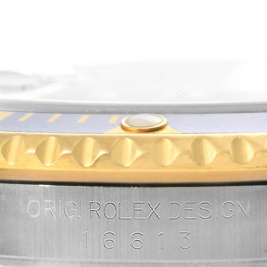 The image shows a close-up of the bezel and side of the case of the Rolex Submariner 16613 Men's Steel and Gold (two tone) Blue Dial 16613 Men's Steel and Gold (two tone) Blue Dial, focusing on engraved text and bezel detailing.