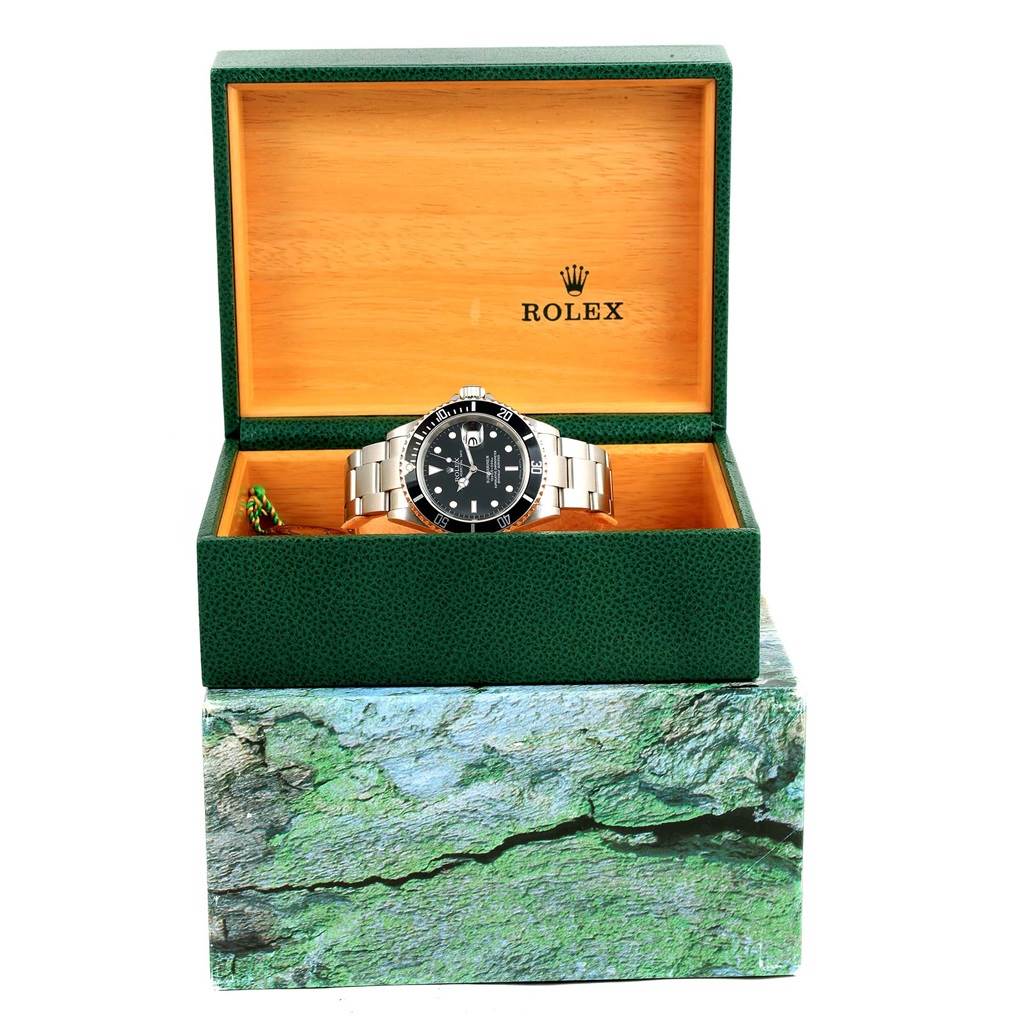 The image shows a Rolex Submariner 16610 Men's Stainless Steel Black Dial 16610 Men's Stainless Steel Black Dial watch in its open green and wooden box, viewed from the front.